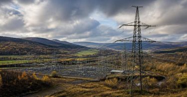 Tralicci e infrastrutture elettriche collegano diverse aree di un territorio europeo.