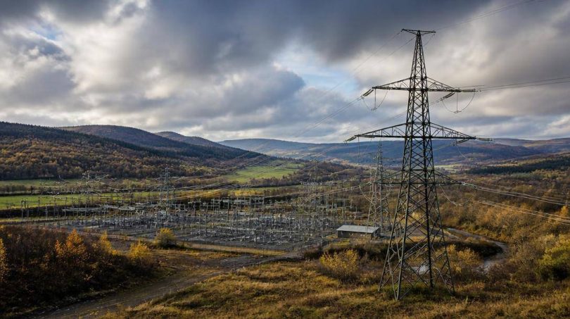 Tralicci e infrastrutture elettriche collegano diverse aree di un territorio europeo.