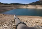 Tecnici ambientali osservano un bacino idrico e le infrastrutture di gestione dell'acqua.