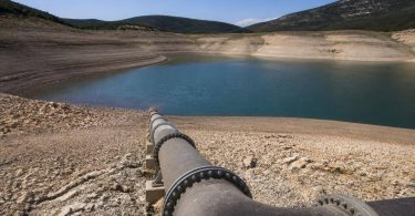 Tecnici ambientali osservano un bacino idrico e le infrastrutture di gestione dell'acqua.