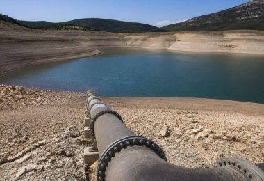 Tecnici ambientali osservano un bacino idrico e le infrastrutture di gestione dell'acqua.