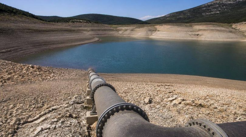 Tecnici ambientali osservano un bacino idrico e le infrastrutture di gestione dell'acqua.