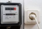 Persona confronta una bolletta elettrica con i consumi rilevati dal contatore domestico.