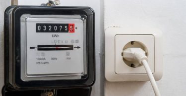 Persona confronta una bolletta elettrica con i consumi rilevati dal contatore domestico.