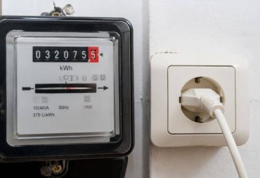 Persona confronta una bolletta elettrica con i consumi rilevati dal contatore domestico.