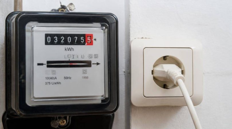 Persona confronta una bolletta elettrica con i consumi rilevati dal contatore domestico.